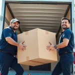Movers calgary team efficiently loading a box into a truck in a sunny urban area.